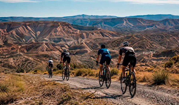 Group of cyclists riding through an arid landscape in Granada